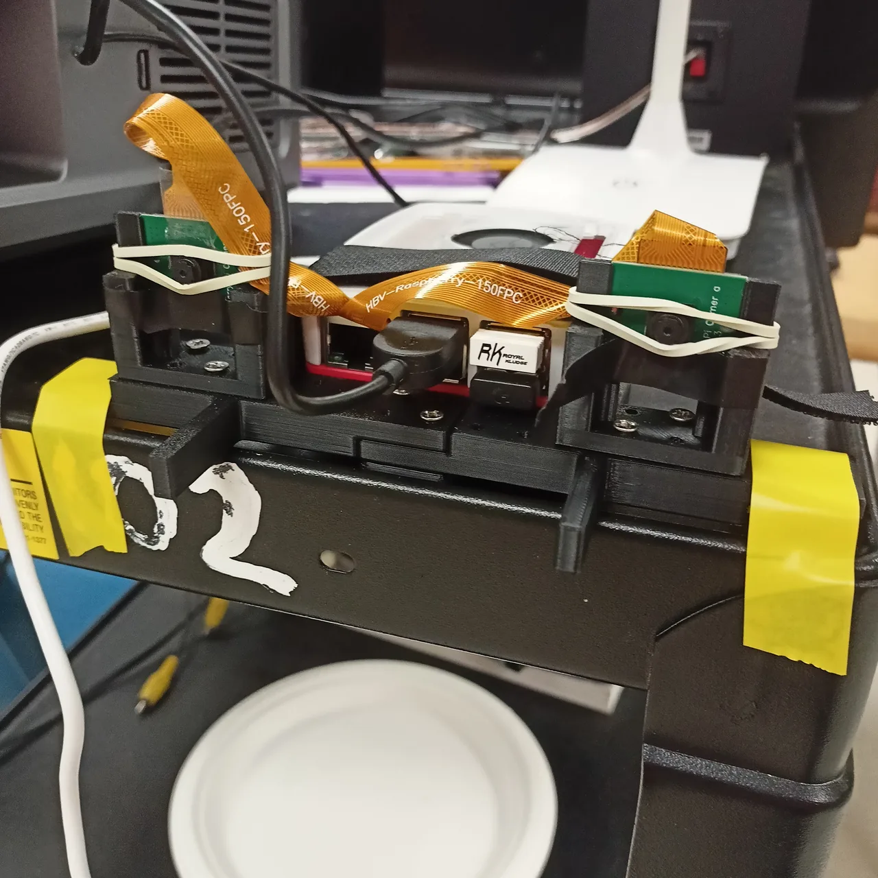 Two cameras held in printed mounts with elastic bands, with a Raspberry Pi between them