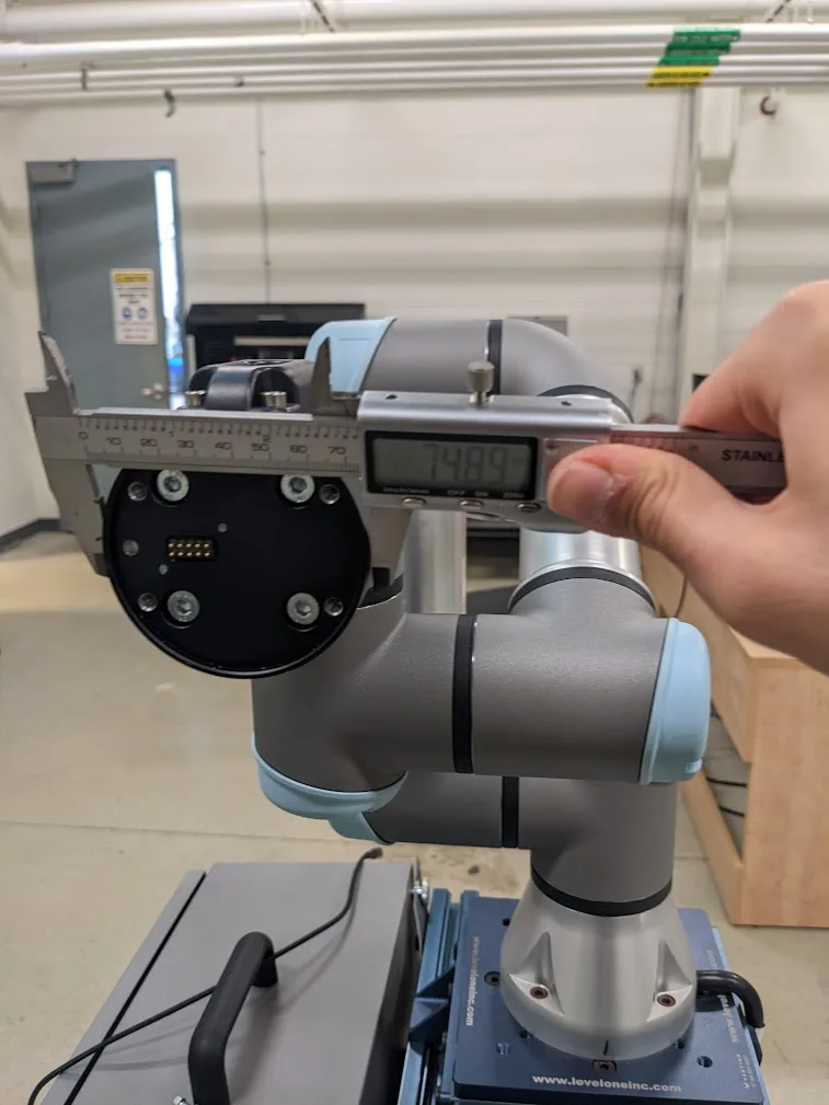 A caliper measuring the robot arm's tool flange